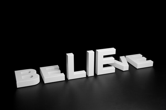 White Believe word lay down with lie word standing on dark background, 3d render
