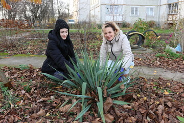 Two women tending to a flowerbed outside