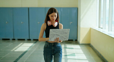 Indian young gen z busy woman lady in hold laptop hand look screen check new email notes walk campus place. Teen girl female pupil use device do exam study online e learn work skill data day time