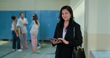 Indian mature adult busy lady woman staff hold use tab look camera e-learning new skill work task...