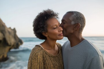 Elderly african couple sharing a tender moment by the ocean at sunset