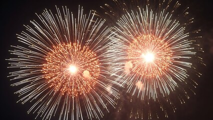 Two bright orange and white fireworks exploding simultaneously in the dark night sky during a festive celebration or holiday event