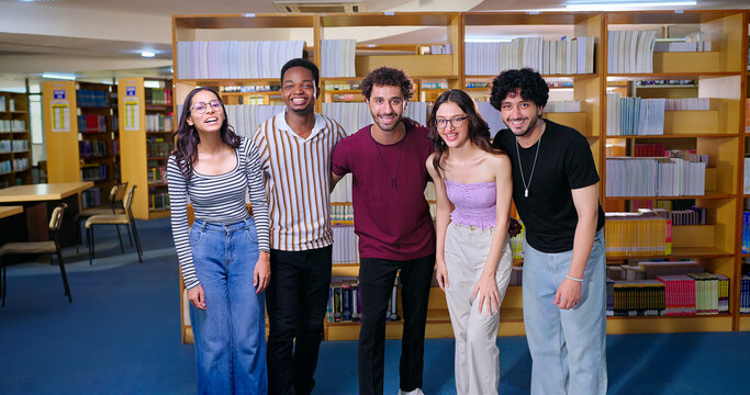 Indian happy young adult gen z cheerful student group standing indoor library look camera together smiling girl male boy man team staring cam do casual pose enjoy day break time