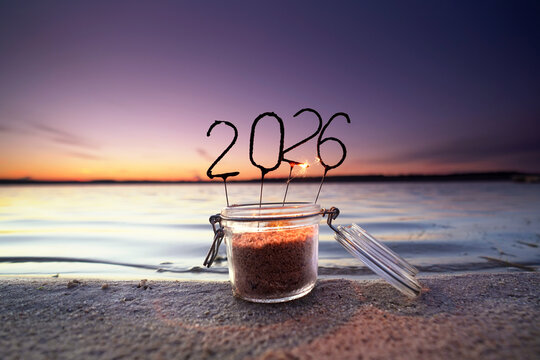 Fototapeta Burned down 2026 Sparklers in a Glass by the Sea  