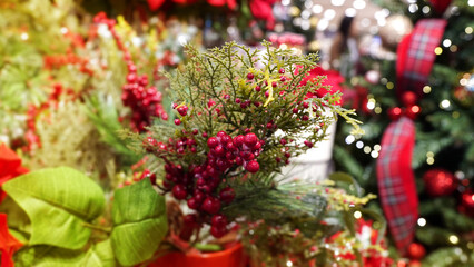 Obraz premium Festive Christmas artificial flower decorations with sparkling lights in holiday shop