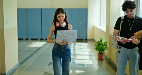 Indian young gen z busy woman lady hold laptop in hand look screen check new email notes walk campus place. Teen girl female pupil use device do exam study online e learning work skill data day time