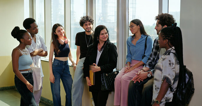 Indian happy young adult tutor lady woman group talk casual gossip have fun joy enjoy new day spend break time indoor place. Teen female girl pupil boy man male guy group mate speak share funny joke