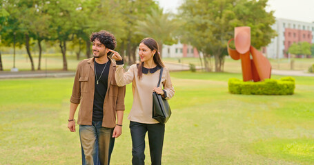 Indian young adult gen z smart male female wear bag walk talk casual gossip share new day plan spend break time place. Happy teen girl cool boy man pupil guy speak funny joke have fun joy garden park