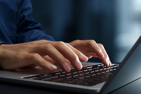Businessperson using laptop computer at desk in office. Closeup of hands and keyboard. Business technologies.