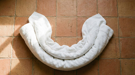 Overhead view of fluffy white towels arranged in concentric curves on terracotta floor