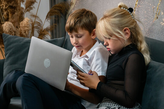 Children Laptop Technology - Two children sit on a couch and use a laptop and tablet. - Powered by Adobe