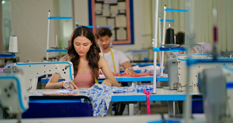 Indian young adult pupil gen z woman wear measure tape around neck sitting class room learn new casual course good sewing machine. focused teen female girl do self craft skill indoor day college place
