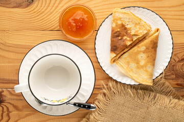 Hot pancakes with apricot jam on a wooden table, macro, top view.