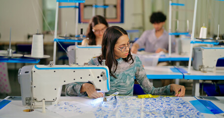 Indian young adult pupil gen z woman wear glasses tape around neck sitting class room learn new casual course good sewing machine. focused teen female girl do self craft skill indoor day college place