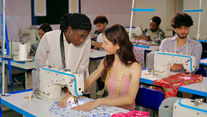 Indian young adult female wear tape around neck sitting indoor class room place woman learn sewing use craft clothe Teen girl student pupil do new course lady talk help teach stitch skill college day