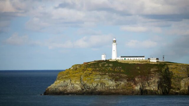 Stormy overcast clouds above flashing south stack lighthouse on remote coastal island of Holyhead