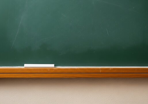 Closeup of a green chalkboard with a piece of white chalk resting on its wooden ledge, ready for writing