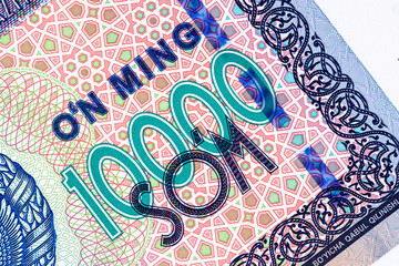 A 2017 banknote of 10000 Uzbek soums. The obverse depicts the state emblem. The reverse side of the banknote features an image of the Senate building in Tashkent.