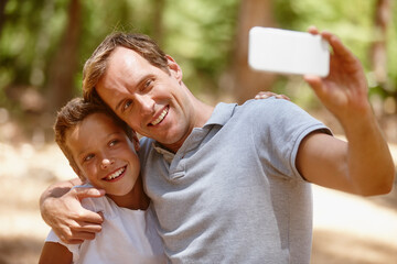 Happy father, son or forest with selfie for picture, photography or outdoor memory together. Dad, child or kid with smile, hug or embrace for capture moment, bonding or family time in nature or woods