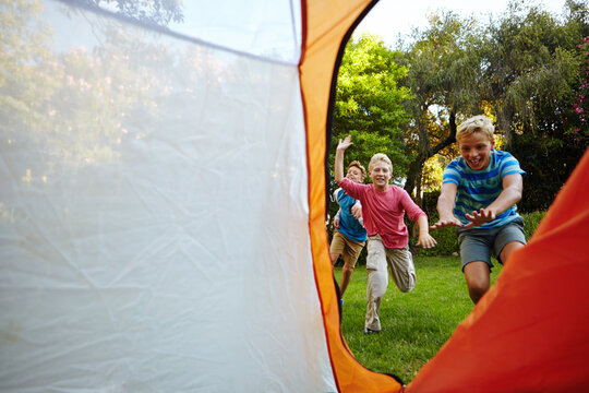 Kids outdoor, game and chasing in tent for camping activity, childhood memories and bonding together. Boys laughing, playing tag and enter shelter in nature for friendship, fun adventure and space.