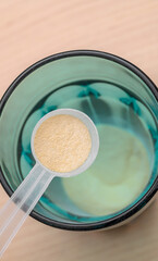 A scoop of creatine for athletes over a glass of water, an isotonic drink for athletes