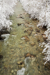 Fast flowing mountain stream framed by snow covered riverbanks