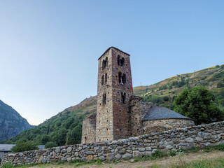 Old stone church nestled in a lush green Pyrenees mountain valley at twilight