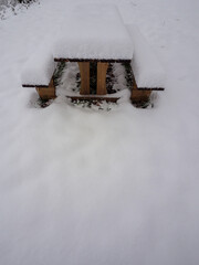 Wooden picnic table covered in deep snow with vast copy space below