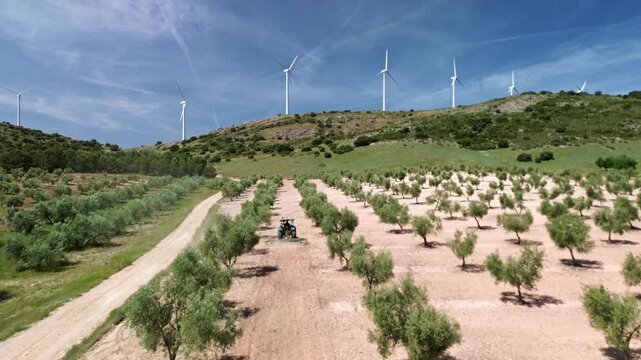 TRACTOR ARANDO OLIVOS EN SIERRA CON MOLINOS EOLICOS