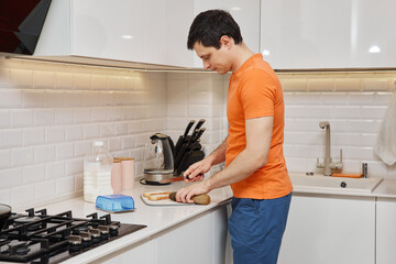Man slicing sausage for breakfast toast in bright domestic kitchen