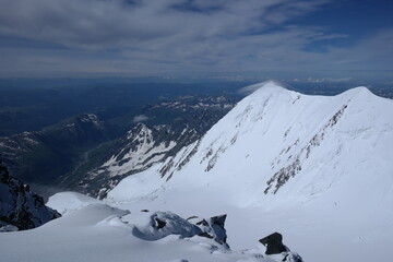 Tranquil Lake With Lush Green Forest, Snow-Capped Mountain, Blue Sky And White Clouds