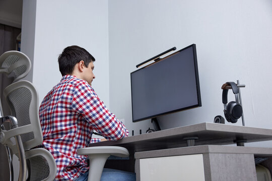 Man focusing on computer screen while sitting in an ergonomic chair at a modern desk