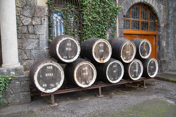 Wooden barrels on the background of an ancient wall at a winery on a clear sunny day. Winemaking viticulture wine blend.
