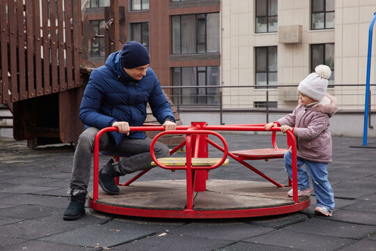 Father and daughter playing on a carousel, bonding and having fun
