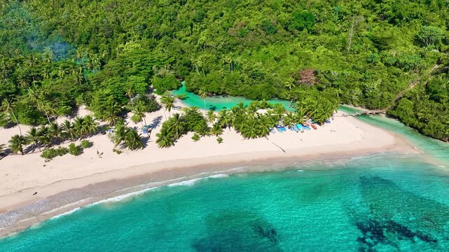 An aerial view of the tropical white sand beach of Rincon with palm trees on a sunny day. The perfect backdrop for a summer vacation in the Dominican Republic. Concept of a beach holiday in a lagoon.