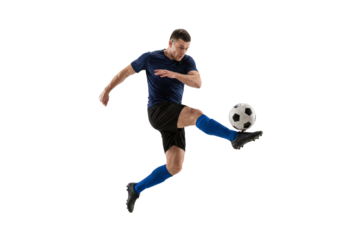 Male soccer player kicking ball in mid air on isolated black background, athletic action and competitive sport concept for training, fitness motivation and team game promotion