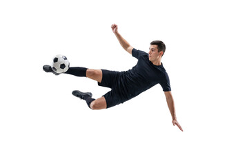 Male soccer player performing flying kick in mid air on isolated black background, athletic action and competitive sports concept for training, fitness promotion and team game energy