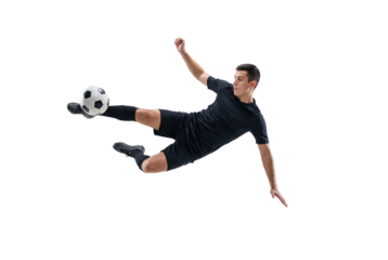 Male soccer player performing flying kick in mid air on isolated black background, athletic action and competitive sports concept for training, fitness promotion and team game energy