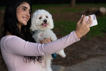 Woman and maltese dog taking happy selfie in park