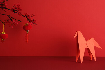 Fototapeta premium Happy Chinse New Year 2026 concept. Red origami horse and two red hanging lanterns against a vibrant red backdrop.