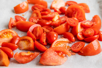 fresh tomato slices and cherry tomatoes on a tray with parchment paper