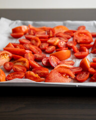 fresh tomato slices and cherry tomatoes on a tray with parchment paper