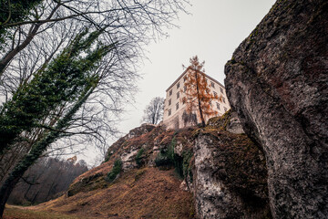 Pieskowa Skała Castle in an autumnal atmosphere. The beautiful Pradnik Valley. Poland. A beautiful rock formation in the foreground
