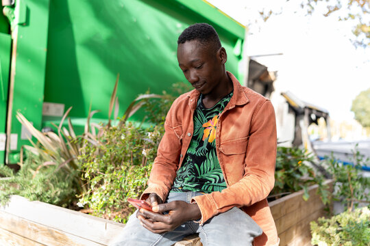 Young man using a smartphone, checking social media or messages in an urban environment - Powered by Adobe
