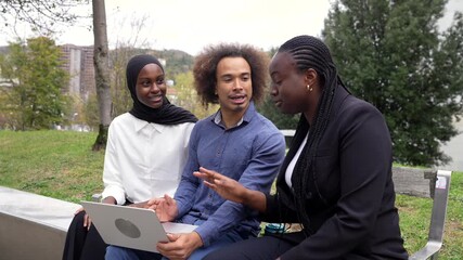 Diverse business team collaborating outdoors using laptop - Powered by Adobe