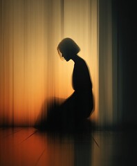Silhouette of woman with head bowed in contemplation, illuminated by a soft, warm light. Minimalist setting.