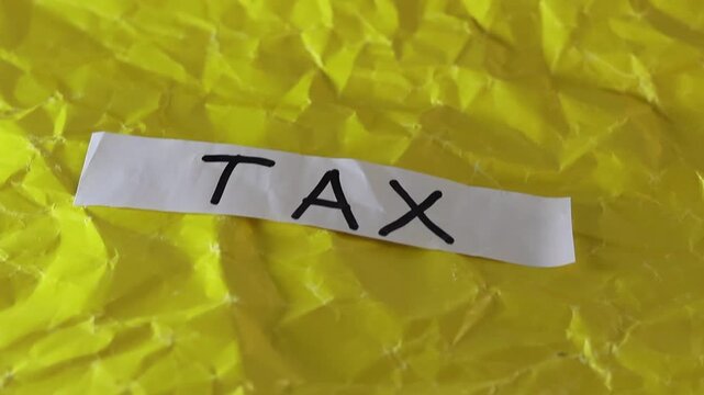 Un primer plano de un papel blanco con la palabra impuesto en un fondo amarillo