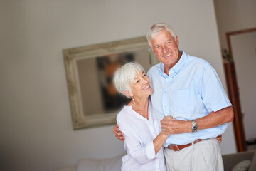 Love, smile and old couple in house with hug, connection and bonding together in retirement. Romance, mature man and woman in lounge with embrace, commitment and relationship security in nursing home