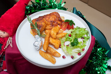 A delightful culinary dish with roasted chicken, potato wedges, fresh salad, and decorative garnishes. The meal is beautifully arranged on a white plate, complemented by festive seasonal decorations.