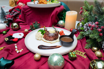 A festive culinary presentation featuring a delicious steak dish surrounded by holiday decorations. This shot captures the essence of a Christmas meal, with a plate of steak, side dishes.